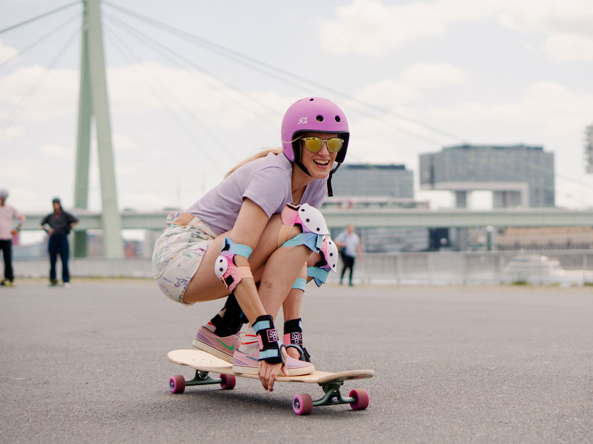 DSCF4010 Eine Frau fährt hockend auf einem Longboard