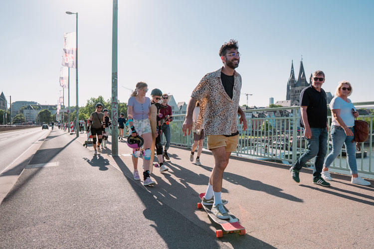 City-tour Ein Longboarder fährt über die Deutzer Brücke in Köln