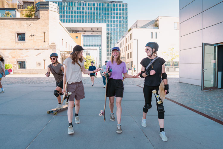 _DSC5858 drei Frauen laufen mit ihrem Longboard durch Köln während des Longboardcamp
