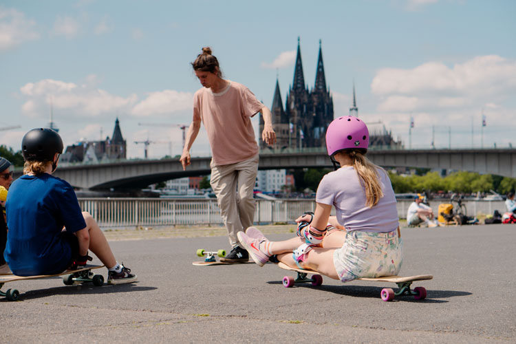 Lessons-3 Ein Trainer zeigt den Teilnehmenden einen Dancing Step auf dem Longboard beim Longboardcamp