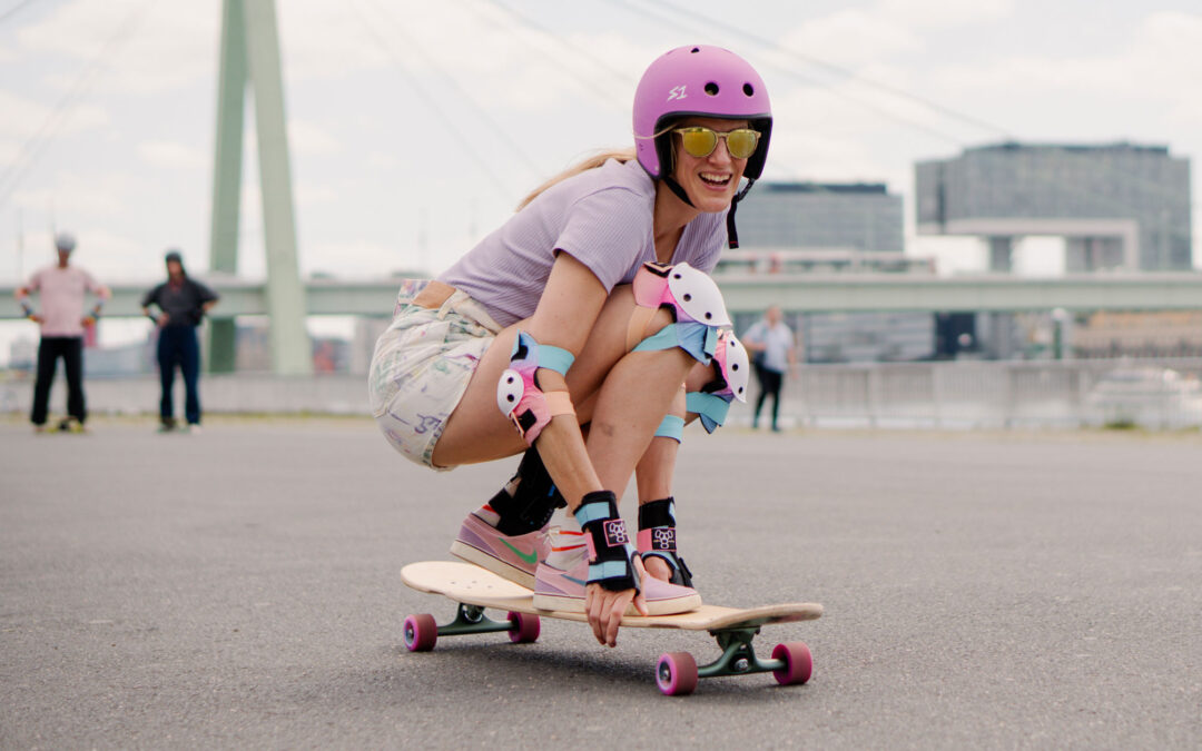 Teilnehmerin Anne vom Longboard Camp fährt sitzend auf ihrem Board