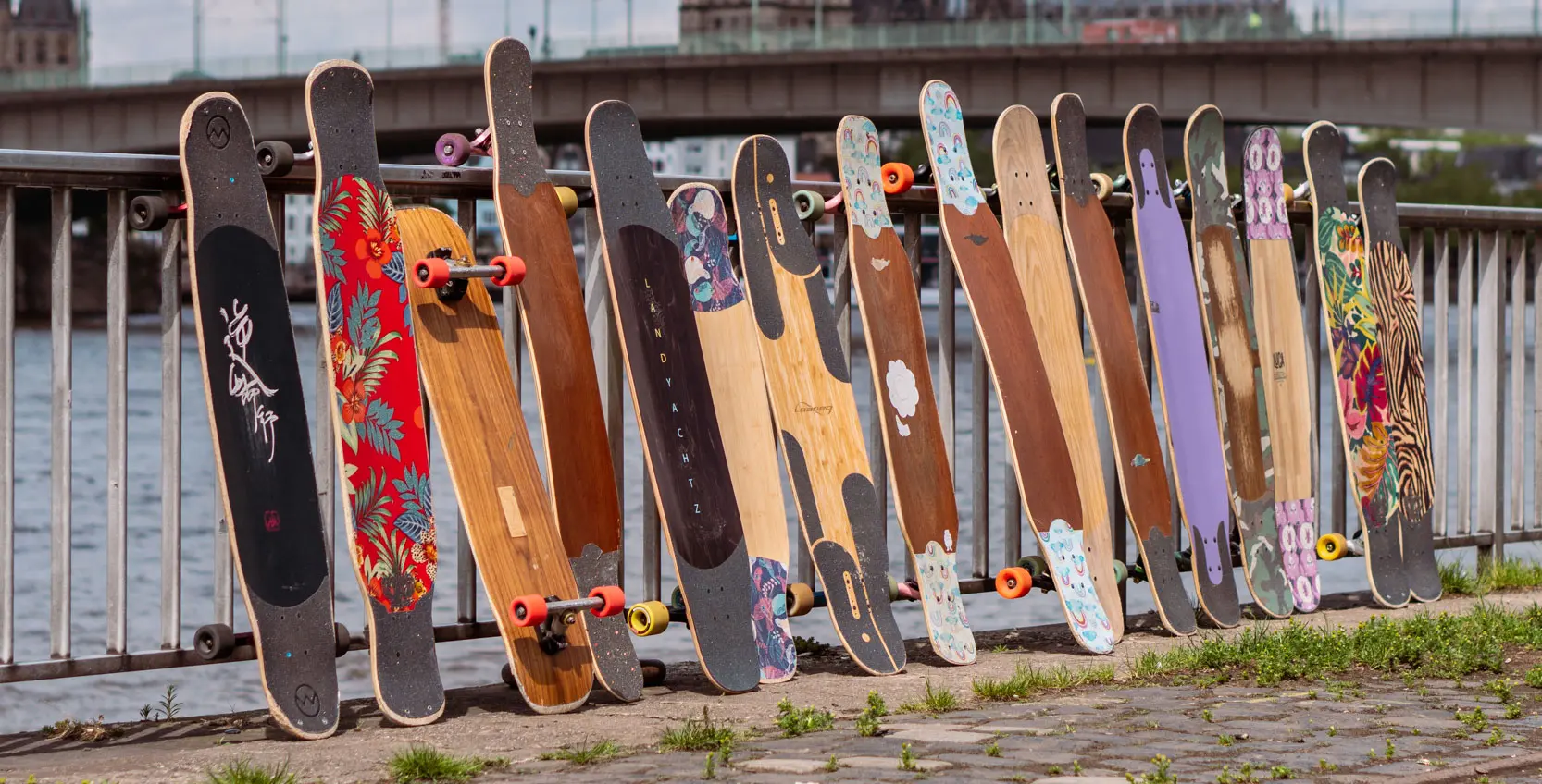 Eine Reihe aus vielen Dancer Longboards steht an einem Geländer in Köln 