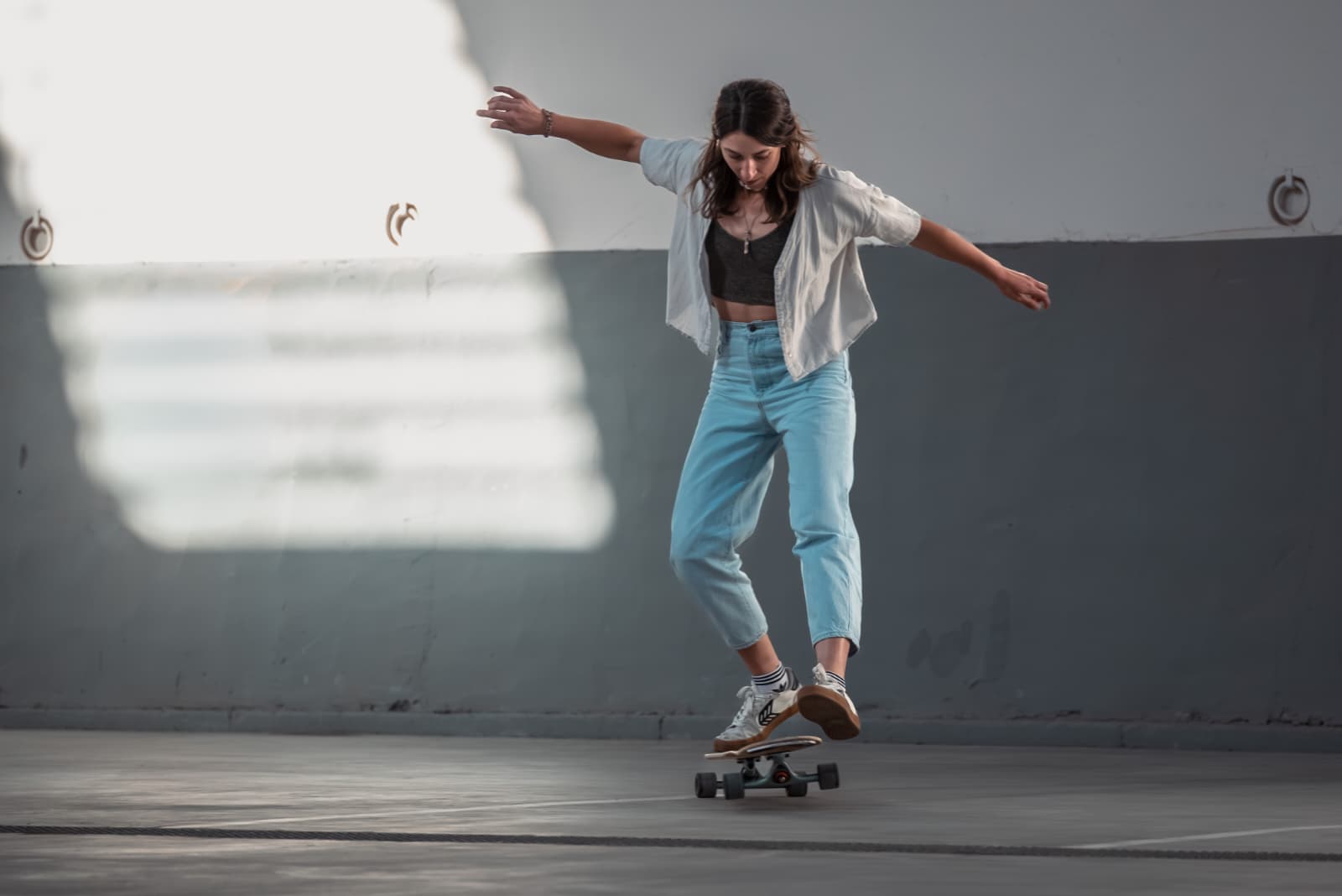 Die Trainerin Franziska, die den Longboard Kurs Essen leitet, steht auf dem Longboard und schaut konzentriert auf ihre Füße
